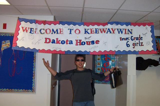 Dakota under a welcome sign in front of the grade 5 & 6 classroom